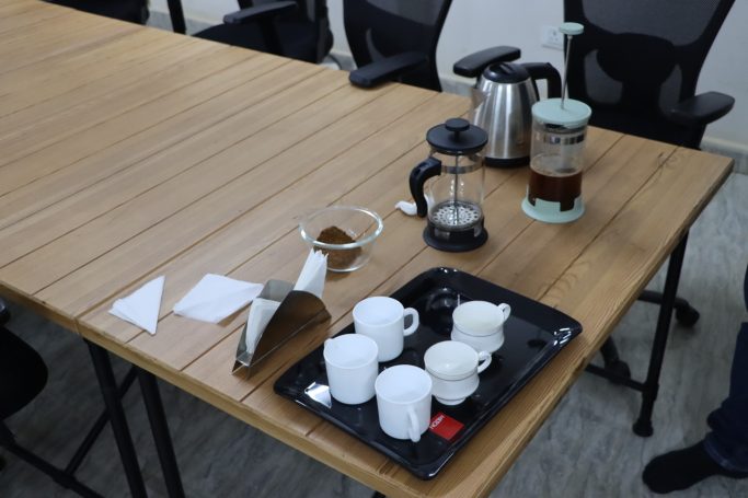 Kaffeetafel mit Kaffeekanne, Brühern und leeren Tassen auf einem Holztisch.